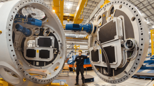 Production line. Assembly of large parts with worker with helmet guiding heavy part