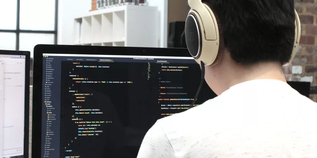 Male developer sitting behind his computer coding with headphones on